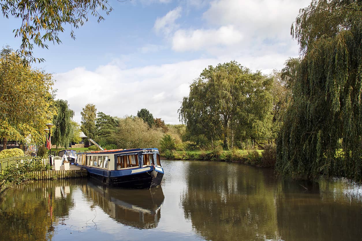 Picturesque landscape of a narrow boat moored on the Avon river awaiting tourists to cruise down the river through Stratford upon Avon, England